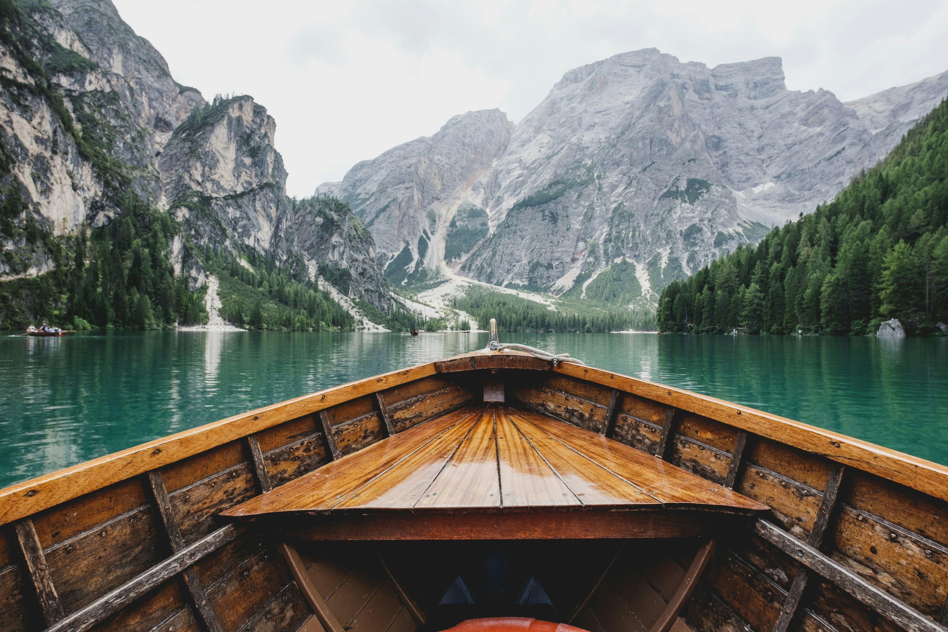 A wooden boat on the still, green water of an alpine lake