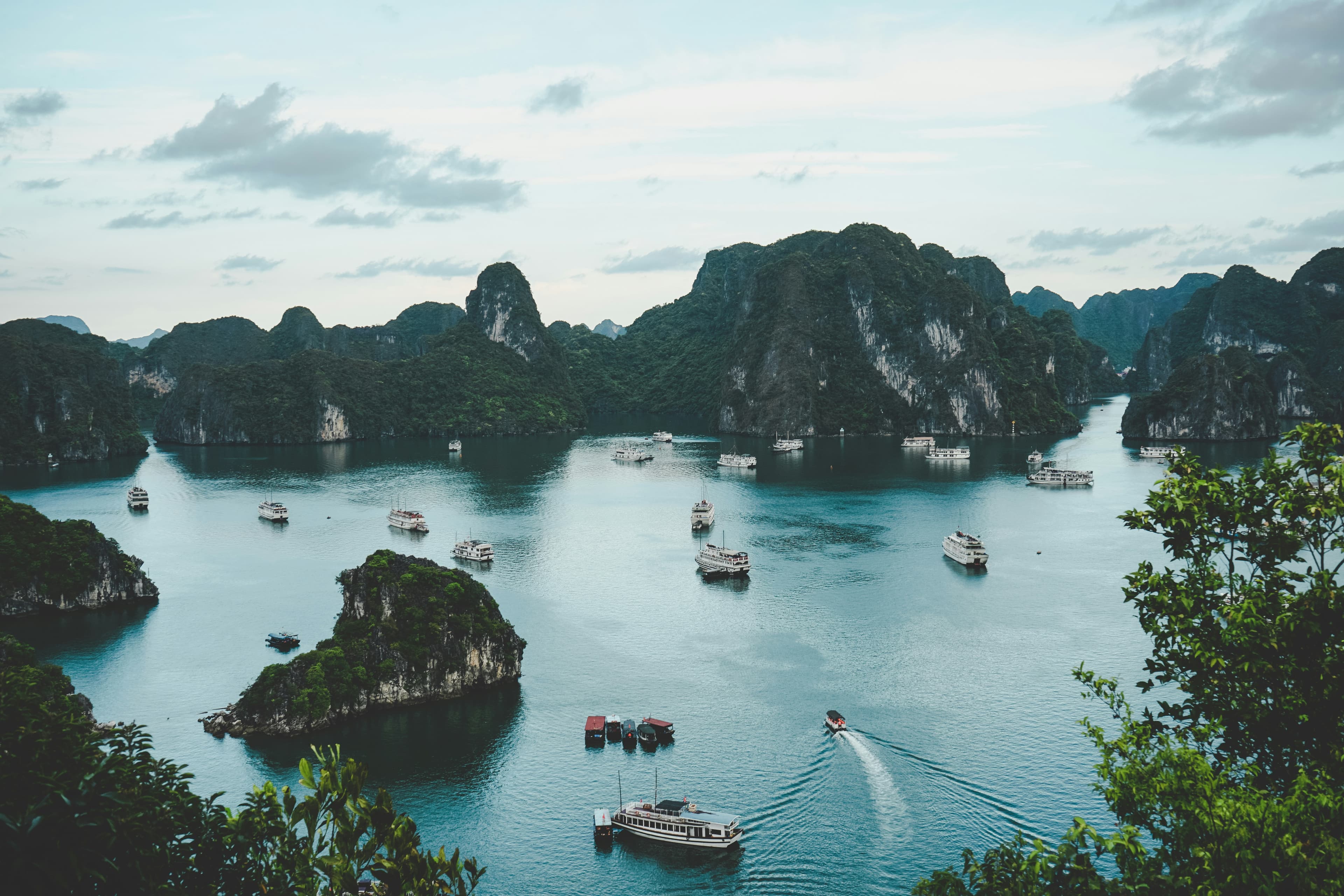 Limestone islands rising from a misty bay dotted with boats